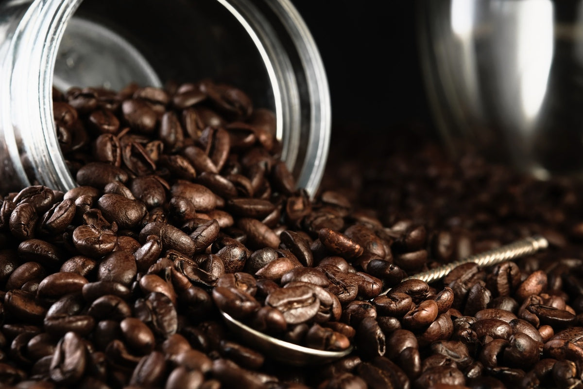 Coffee beans scattered from a jar onto the countertop